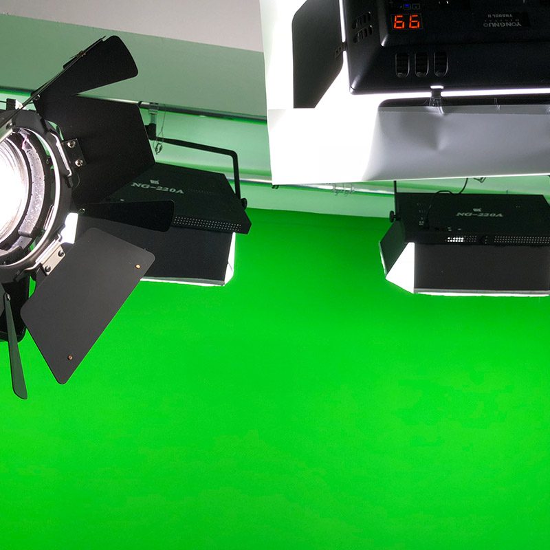 Ein Spot-Light und drei Scheinwerfer vor der grünen Wand.